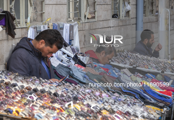 Iranian vendors sit next to their goods on a sidewalk near a bazaar in the historical city of Tabriz, Iran, on October 17, 2024. 