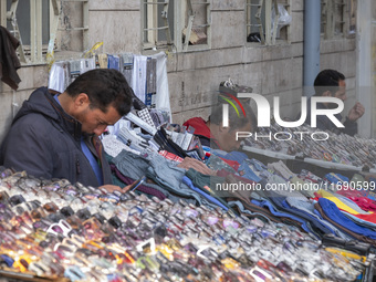 Iranian vendors sit next to their goods on a sidewalk near a bazaar in the historical city of Tabriz, Iran, on October 17, 2024. (