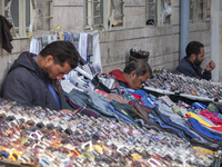 Iranian vendors sit next to their goods on a sidewalk near a bazaar in the historical city of Tabriz, Iran, on October 17, 2024. (