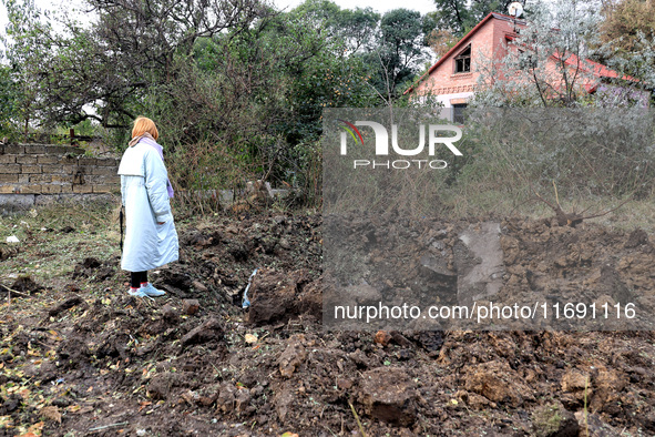 A woman stands at a crater in the ground after the October 18 Russian missile strike in Odesa, Ukraine, on October 19, 2024. 