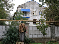 A man stands on a stump and looks at a sanatorium damaged by the October 18 Russian missile strike from behind a brick fence in Odesa, Ukrai...