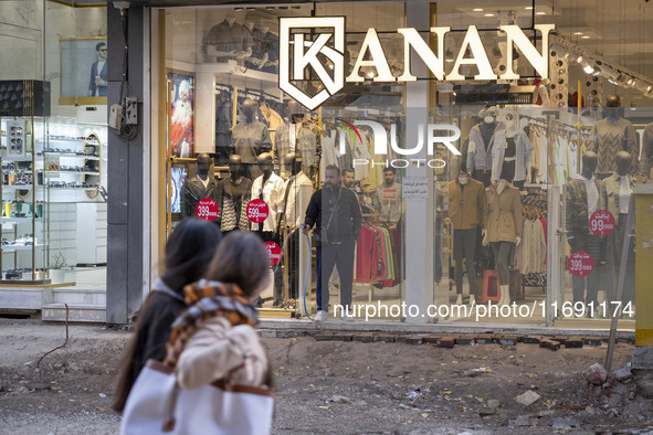 An Iranian shopkeeper sprinkles water on the street under repair to prevent dirt in the historical city of Tabriz, located 624 km (388 miles...