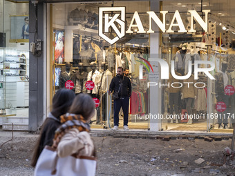 An Iranian shopkeeper sprinkles water on the street under repair to prevent dirt in the historical city of Tabriz, located 624 km (388 miles...