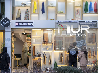 Iranian people look at scarves decorated in a scarf shop window in the historical city of Tabriz, located 624 km (388 miles) northwest of Te...