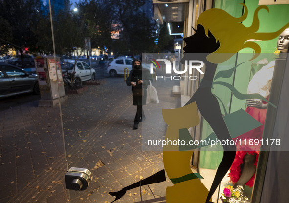 An Iranian woman walks past a dress shop at sunset in the historical city of Tabriz, Iran, on October 17, 2024. 