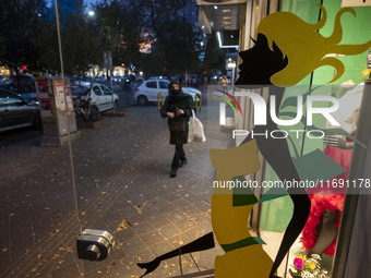 An Iranian woman walks past a dress shop at sunset in the historical city of Tabriz, Iran, on October 17, 2024. (