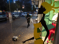 An Iranian woman walks past a dress shop at sunset in the historical city of Tabriz, Iran, on October 17, 2024. (