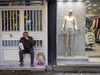 An Iranian vendor smokes a cigarette while sitting next to a mannequin decorated at a shop window in the historical city of Tabriz, Iran, on...