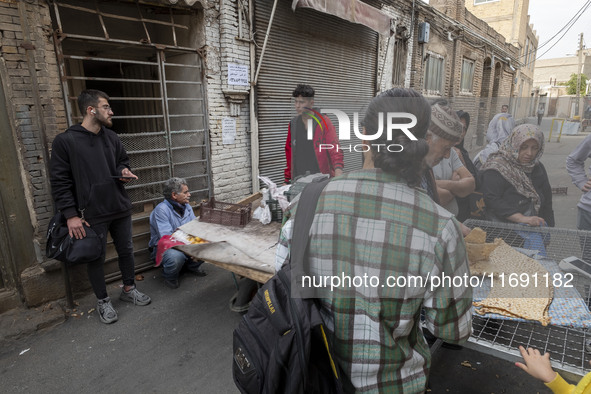 Iranian people stand in front of a traditional bakery while waiting to receive bread in the historical city of Tabriz, Iran, on October 17,...