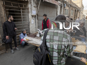 Iranian people stand in front of a traditional bakery while waiting to receive bread in the historical city of Tabriz, Iran, on October 17,...