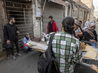 Iranian people stand in front of a traditional bakery while waiting to receive bread in the historical city of Tabriz, Iran, on October 17,...