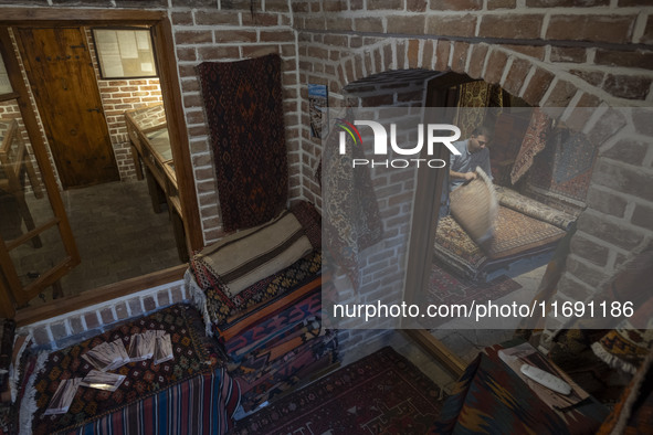 An Iranian man looks at an old Persian handwoven rug at a cultural center in the historical city of Tabriz, located 624 km (388 miles) north...