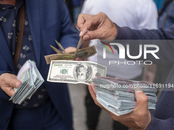 Iranian street money changers hold USD banknotes while standing on a sidewalk in the historical city of Tabriz, located 624 km (388 miles) n...