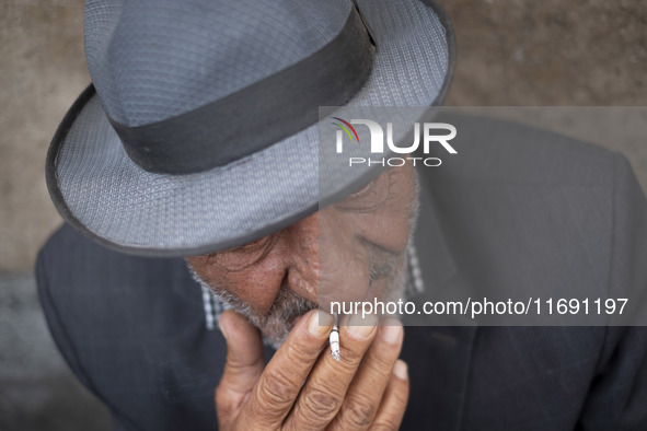 An elderly Iranian man smokes a cigarette while sitting on a sidewalk in the historical city of Tabriz, located 624 km (388 miles) northwest...