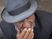 An elderly Iranian man smokes a cigarette while sitting on a sidewalk in the historical city of Tabriz, located 624 km (388 miles) northwest...