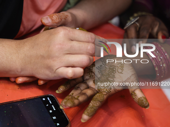 A woman has a mehndi (henna) design applied to her hand during the Diwali and Karwa Chauth Bazaar in Mississauga, Ontario, Canada, on Octobe...