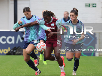 In Dagenham, England, on October 20, 2024, Kyra Cooney-Cross of Arsenal Women, Viviane Asseyi of West Ham United, and Emily Fox of Arsenal c...