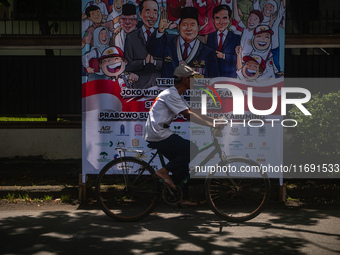 Several motorists pass by a banner expressing congratulations to the elected presidential pair for the 2024-2029 period, Prabowo Subianto-Gi...