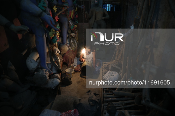 An artist works on a clay face of an idol of the Hindu goddess Kali inside a workshop ahead of the Kali Puja festival in Kolkata, India, on...