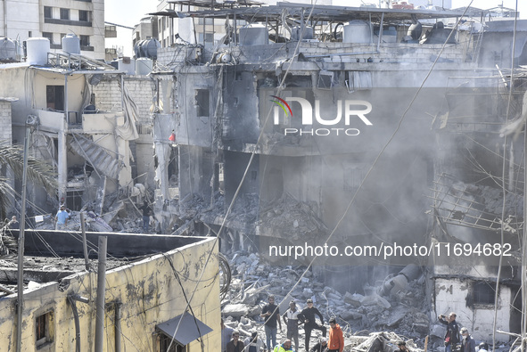 Civilians, paramedics, and Civil Defense Search and Rescue teams conduct search and rescue operations among the rubble of collapsed building...