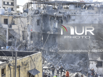 Civilians, paramedics, and Civil Defense Search and Rescue teams conduct search and rescue operations among the rubble of collapsed building...