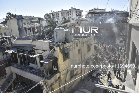 Civilians, paramedics, and Civil Defense Search and Rescue teams conduct search and rescue operations among the rubble of collapsed building...