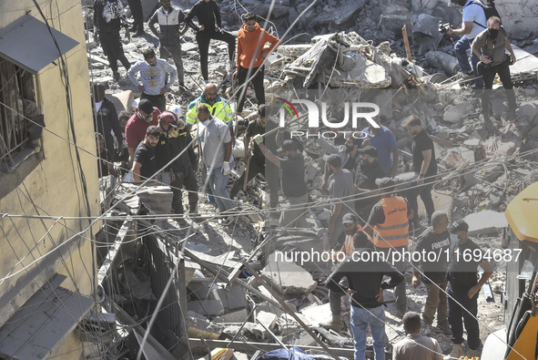 Civilians, paramedics, and Civil Defense Search and Rescue teams conduct search and rescue operations among the rubble of collapsed building...