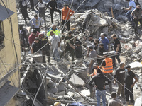 Civilians, paramedics, and Civil Defense Search and Rescue teams conduct search and rescue operations among the rubble of collapsed building...