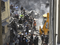 Civilians, paramedics, and Civil Defense Search and Rescue teams conduct search and rescue operations among the rubble of collapsed building...