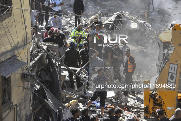 Civilians, paramedics, and Civil Defense Search and Rescue teams conduct search and rescue operations among the rubble of collapsed building...