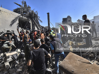 Civilians, paramedics, and Civil Defense Search and Rescue teams conduct search and rescue operations among the rubble of collapsed building...