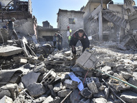 Civilians, paramedics, and Civil Defense Search and Rescue teams conduct search and rescue operations among the rubble of collapsed building...