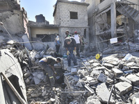 Civilians, paramedics, and Civil Defense Search and Rescue teams conduct search and rescue operations among the rubble of collapsed building...