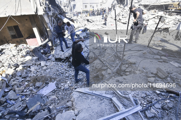 Civilians, paramedics, and Civil Defense Search and Rescue teams conduct search and rescue operations among the rubble of collapsed building...