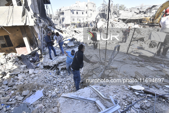 Civilians, paramedics, and Civil Defense Search and Rescue teams conduct search and rescue operations among the rubble of collapsed building...