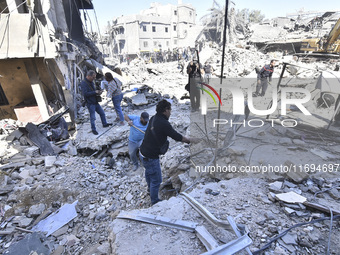 Civilians, paramedics, and Civil Defense Search and Rescue teams conduct search and rescue operations among the rubble of collapsed building...