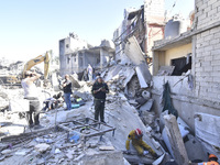 Civilians, paramedics, and Civil Defense Search and Rescue teams conduct search and rescue operations among the rubble of collapsed building...