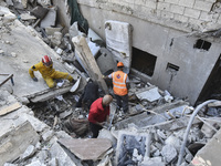 Civilians, paramedics, and Civil Defense Search and Rescue teams conduct search and rescue operations among the rubble of collapsed building...