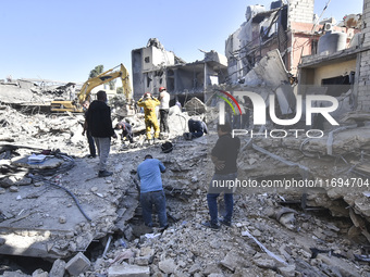 Civilians, paramedics, and Civil Defense Search and Rescue teams conduct search and rescue operations among the rubble of collapsed building...