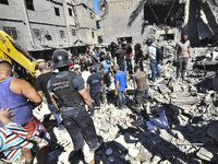 Civilians, paramedics, and Civil Defense Search and Rescue teams conduct search and rescue operations among the rubble of collapsed building...