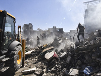 Civilians, paramedics, and Civil Defense Search and Rescue teams conduct search and rescue operations among the rubble of collapsed building...