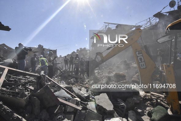 Civilians, paramedics, and Civil Defense Search and Rescue teams conduct search and rescue operations among the rubble of collapsed building...