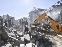 Civilians, paramedics, and Civil Defense Search and Rescue teams conduct search and rescue operations among the rubble of collapsed building...