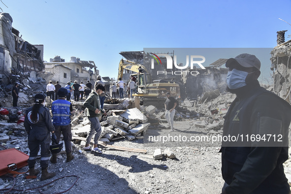 Civilians, paramedics, and Civil Defense Search and Rescue teams conduct search and rescue operations among the rubble of collapsed building...