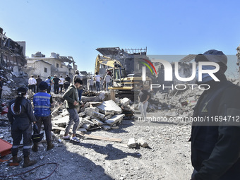 Civilians, paramedics, and Civil Defense Search and Rescue teams conduct search and rescue operations among the rubble of collapsed building...