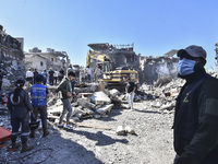 Civilians, paramedics, and Civil Defense Search and Rescue teams conduct search and rescue operations among the rubble of collapsed building...