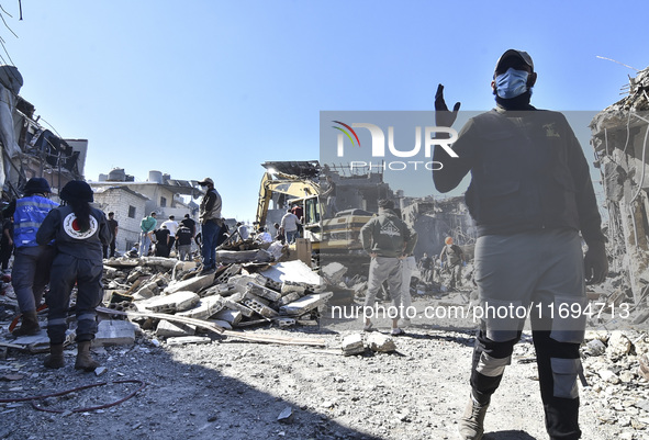 Civilians, paramedics, and Civil Defense Search and Rescue teams conduct search and rescue operations among the rubble of collapsed building...