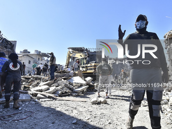 Civilians, paramedics, and Civil Defense Search and Rescue teams conduct search and rescue operations among the rubble of collapsed building...