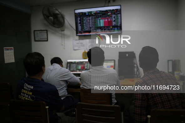 Traders look up at a screen during the Dhaka Stock Exchange trading session at a Brokerage House in Dhaka, Bangladesh, on October 22, 2024. 