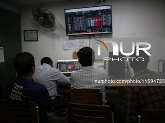 Traders look up at a screen during the Dhaka Stock Exchange trading session at a Brokerage House in Dhaka, Bangladesh, on October 22, 2024....